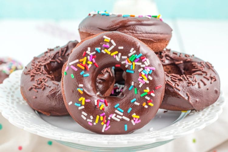 Close up of sprinkled chocolate donuts on plate with blue background