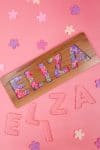 "Eliza" name puzzle on pink background with clear E-L-I-Z-A acrylic puzzle pieces and flowers