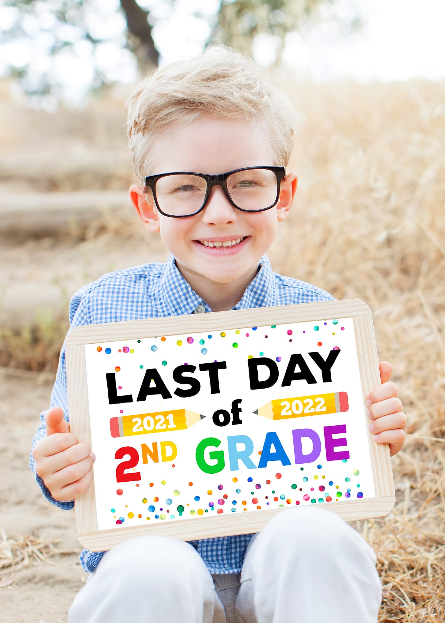 Blonde boy with glasses holding a Last Day of School sign