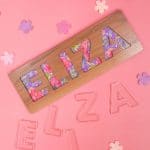 "Eliza" name puzzle on pink background with clear E-L-I-Z-A acrylic puzzle pieces