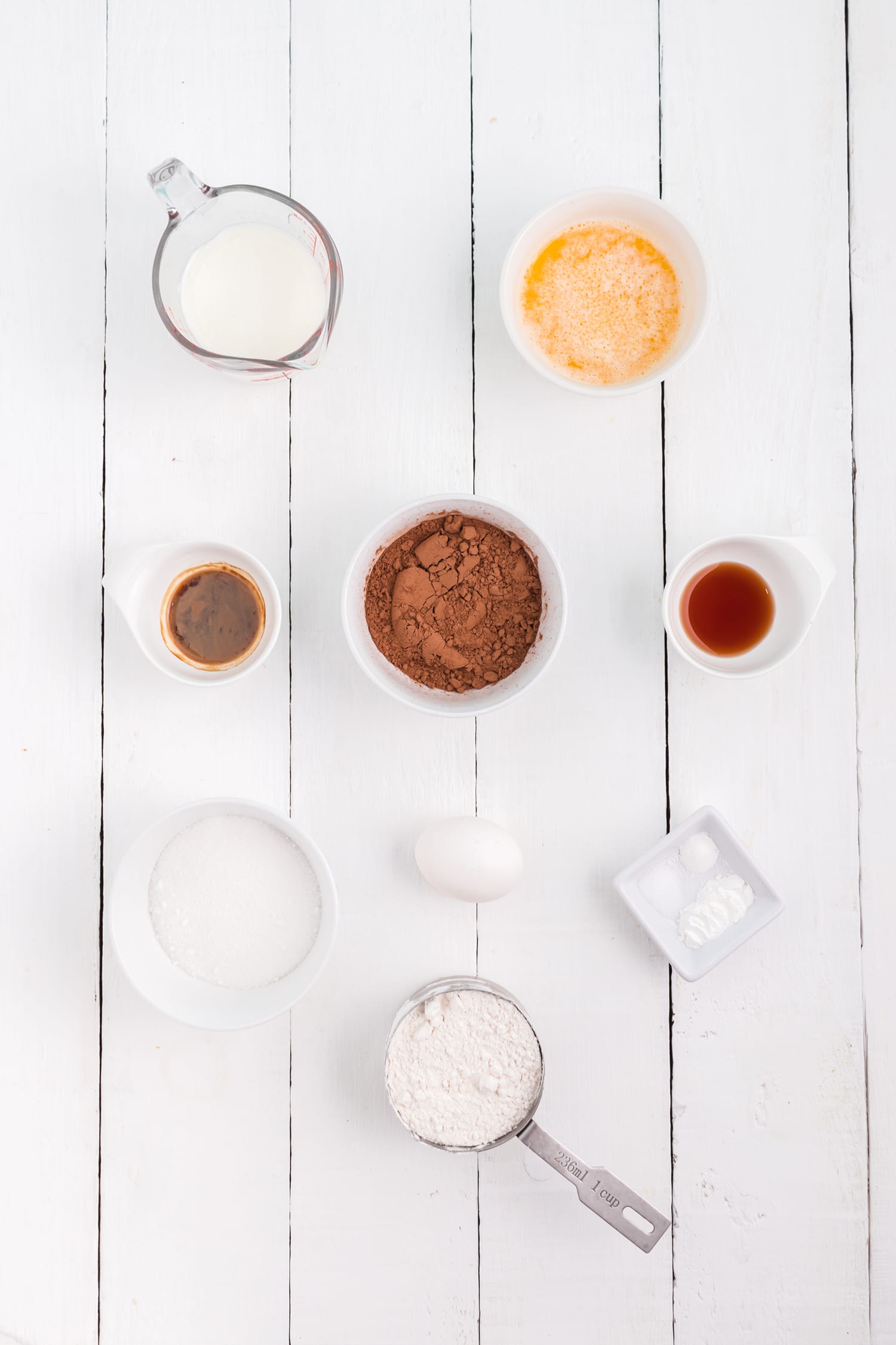 chocolate donut recipe ingredients in bowls on white wood background