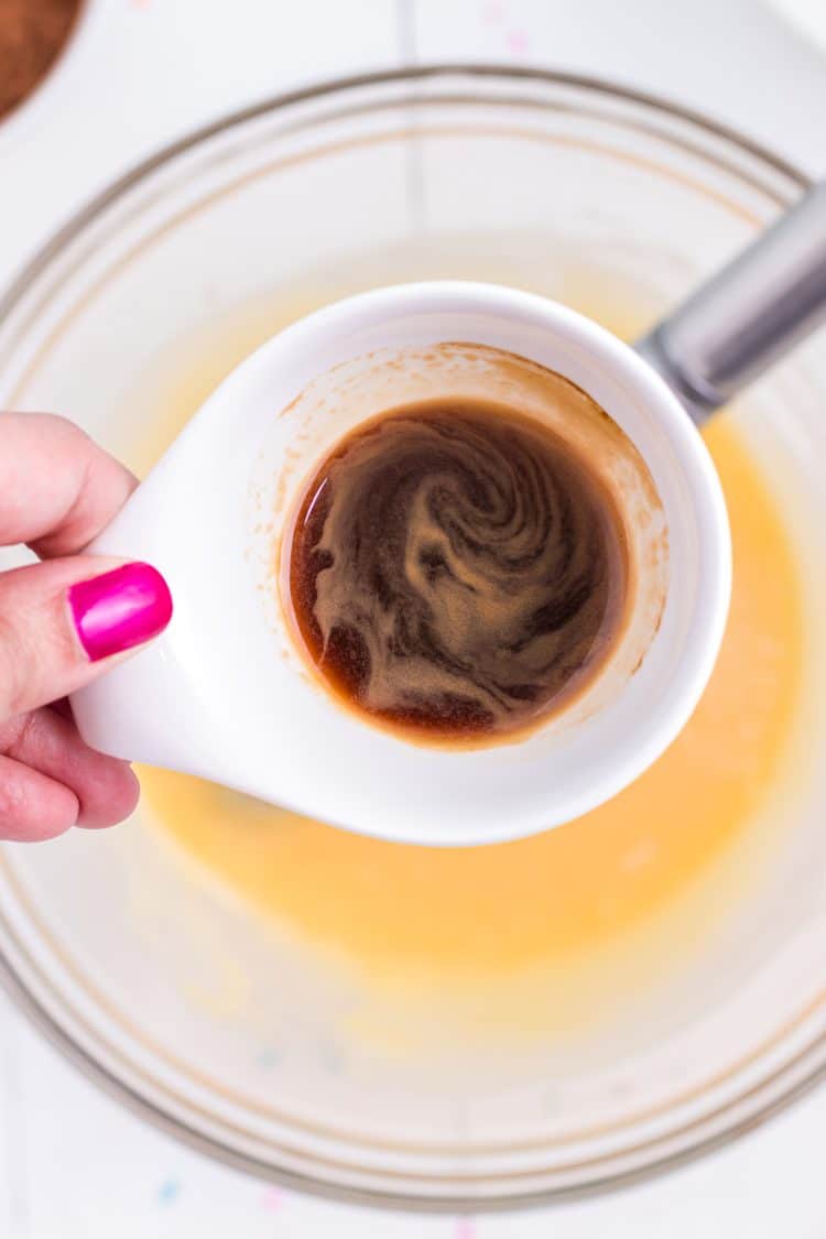 Adding espresso to chocolate donut recipe in mixing bowl