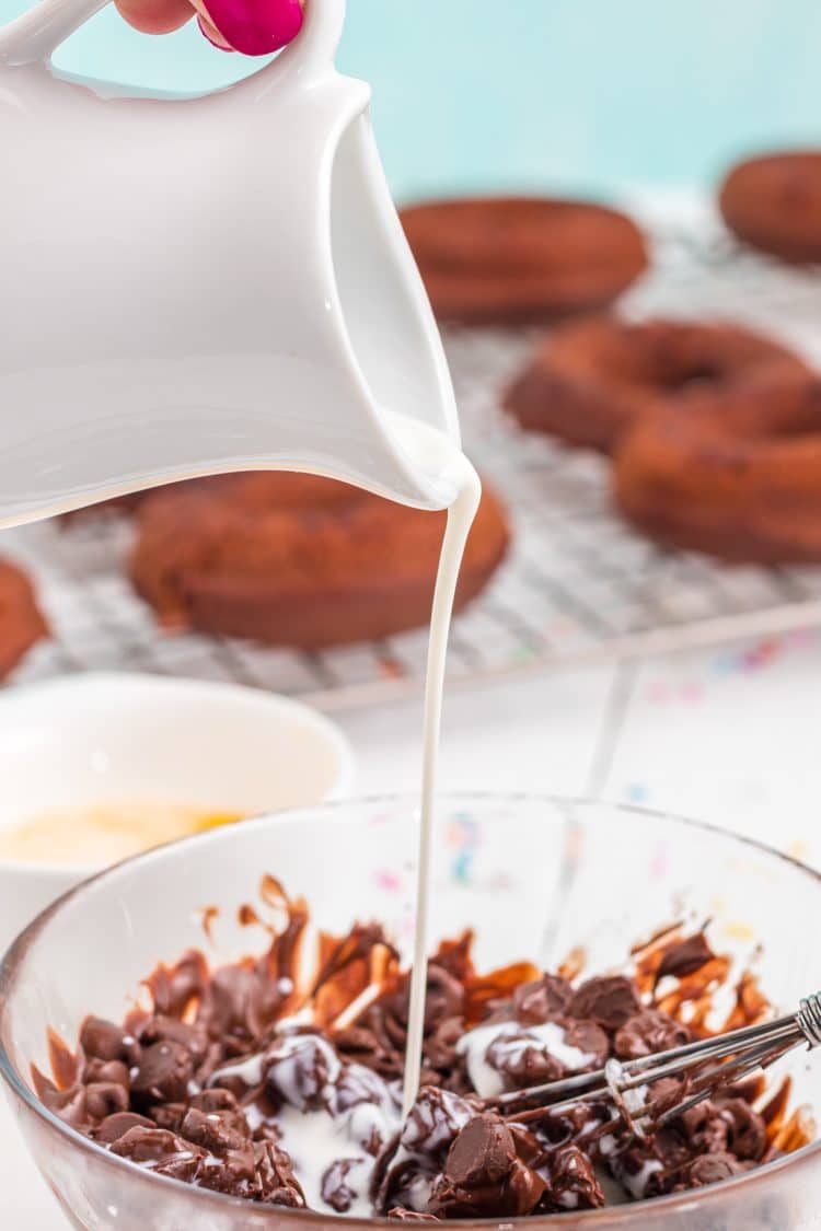 Pouring cream from a pitcher into bowl of melted chocolate for ganache