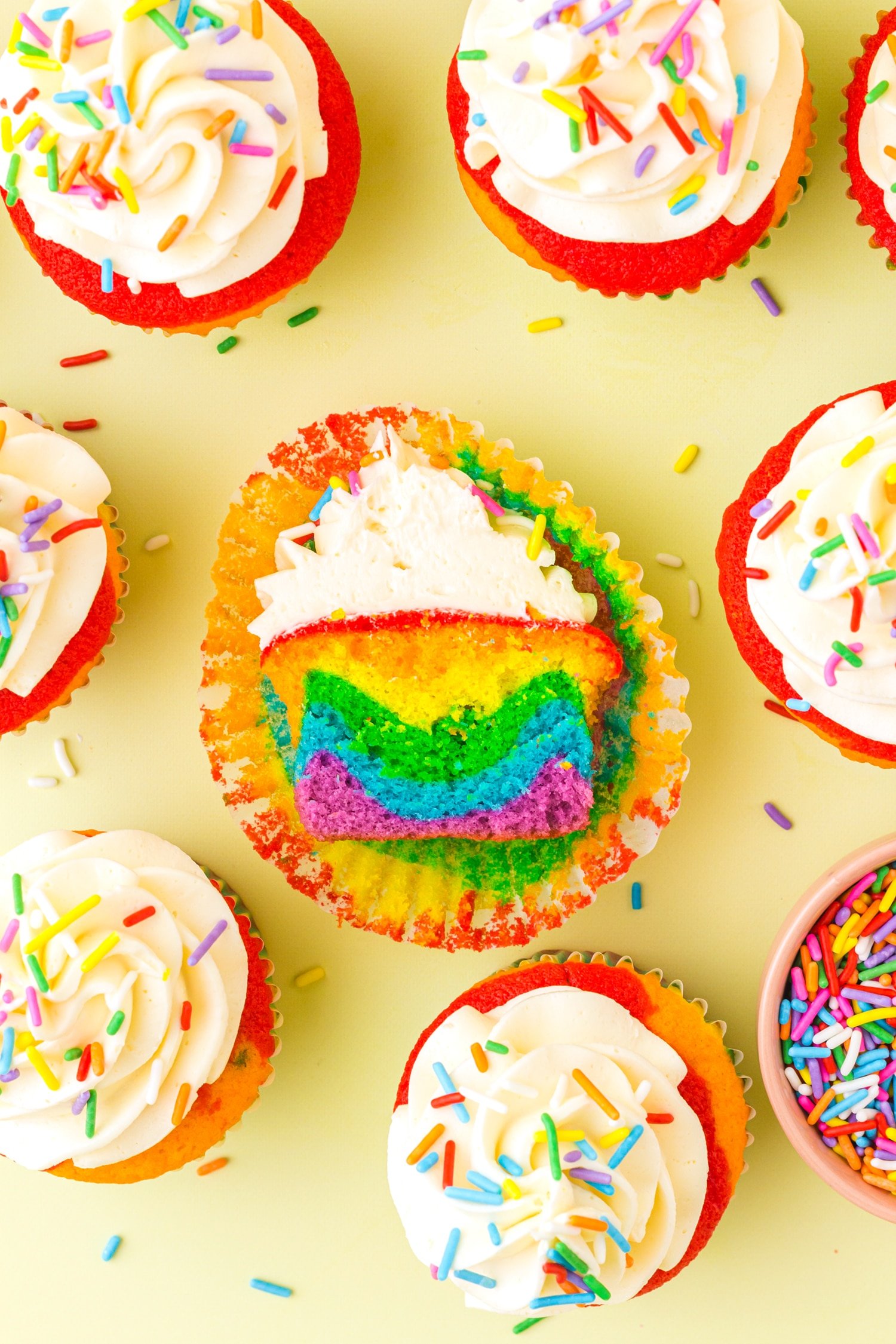 Rainbow Cupcake cut in half on a yellow background