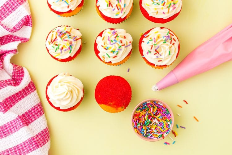 Icing Rainbow Cupcakes with Vanilla Buttercream Frosting on a yellow background