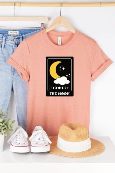 moon tarot card svg file on salmon colored shirt styled with jeans hat and shoes