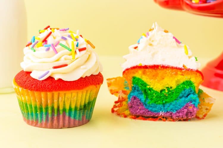 two Rainbow Cupcakes with white frosting and rainbow sprinkles