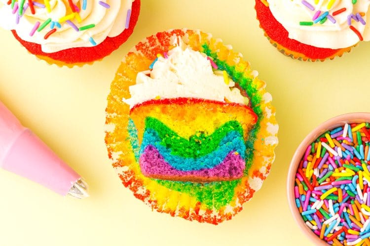 Yummy Rainbow Cupcakes with Vanilla Buttercream Frosting on yellow background