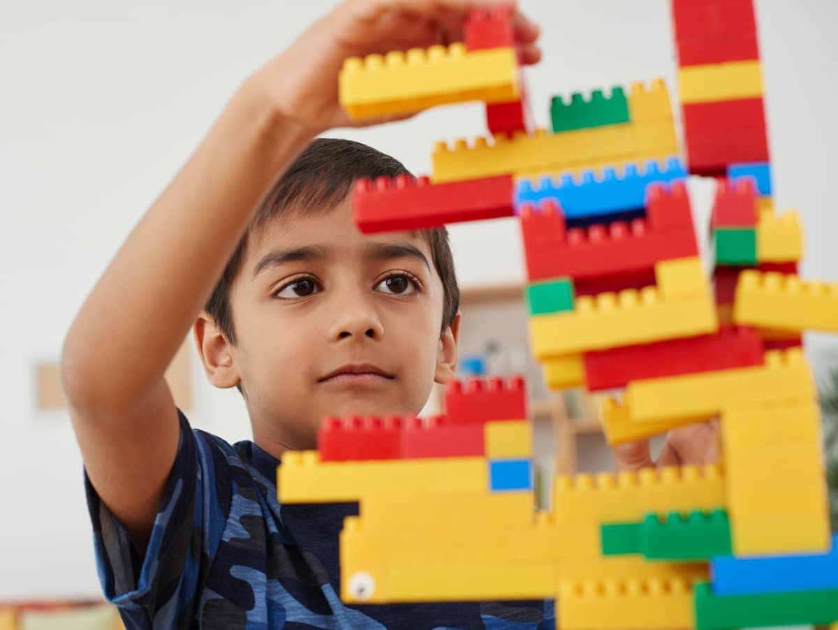 Small Indian boy concentrated on building a block tower