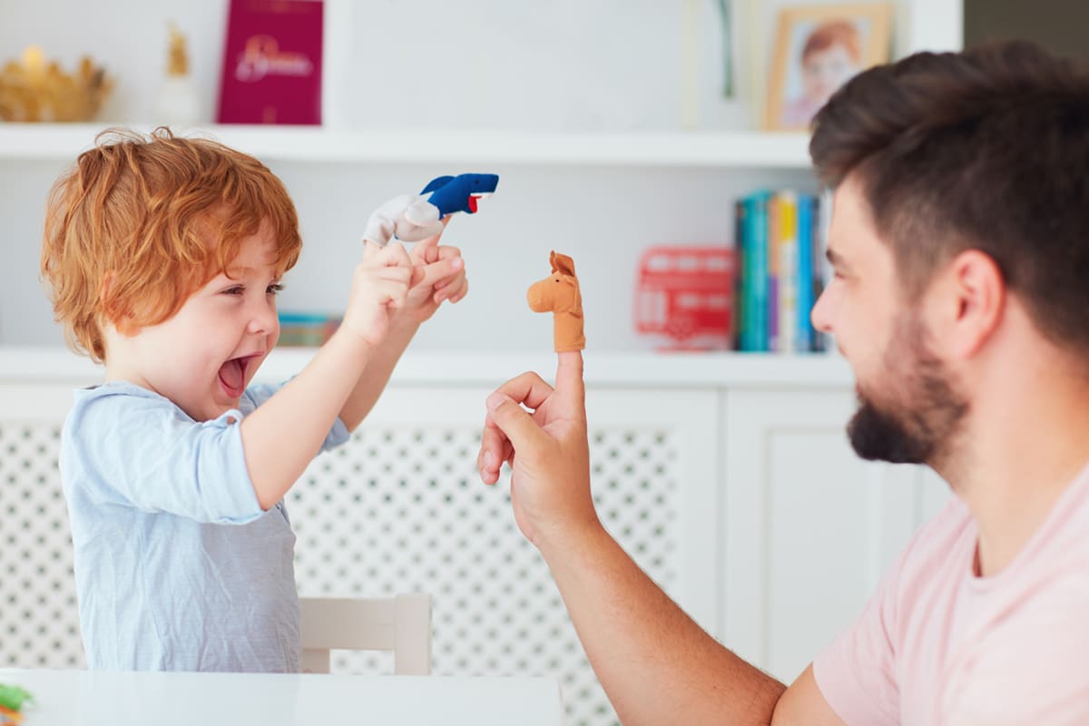 happy father playing finger puppets with son