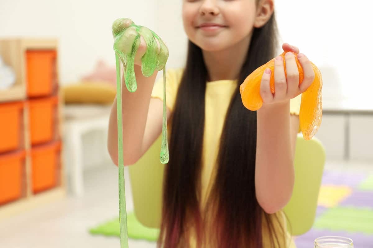 Close up of tween girl playing with orange and green slime