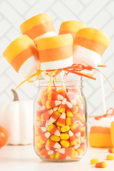 Candy Corn Marshmallow pops in a glass jar filled with candy corn
