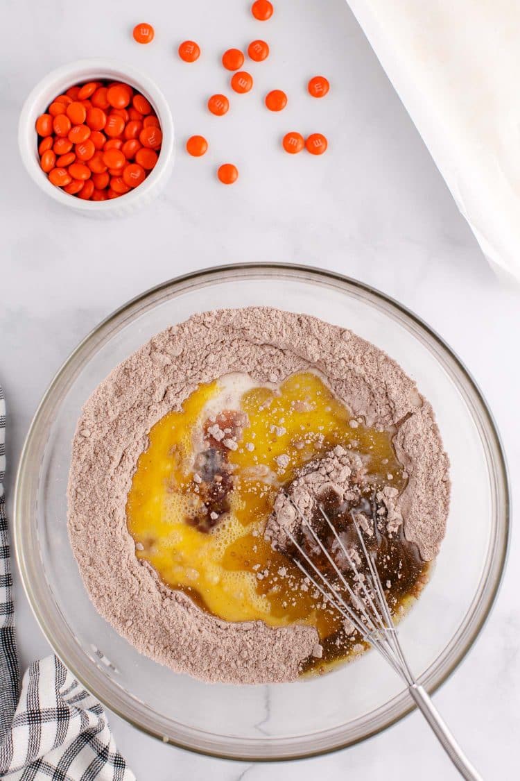 Mixing eggs into chocolate cake mix in a glass bowl.