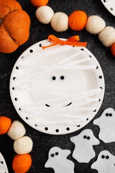 Paper plate mummy craft with halloween background