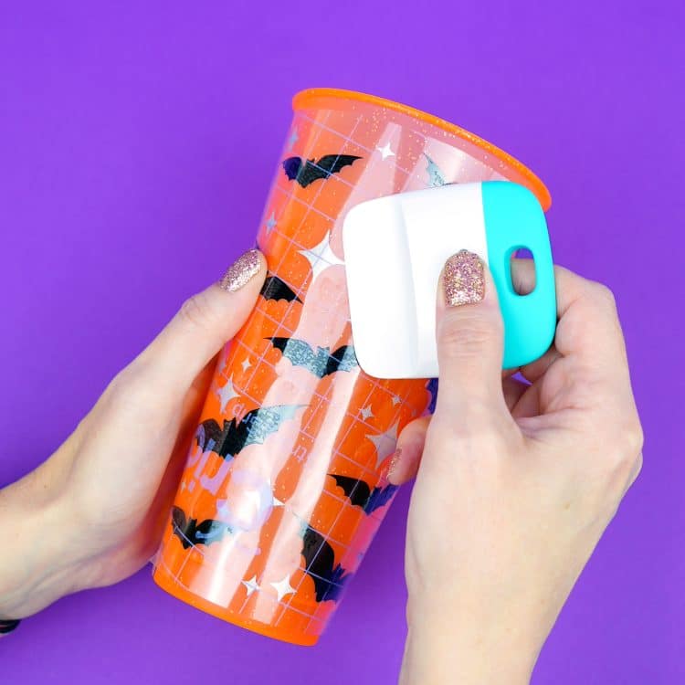 pressing down vinyl on orange drink cup with straw decorated with bats svg files