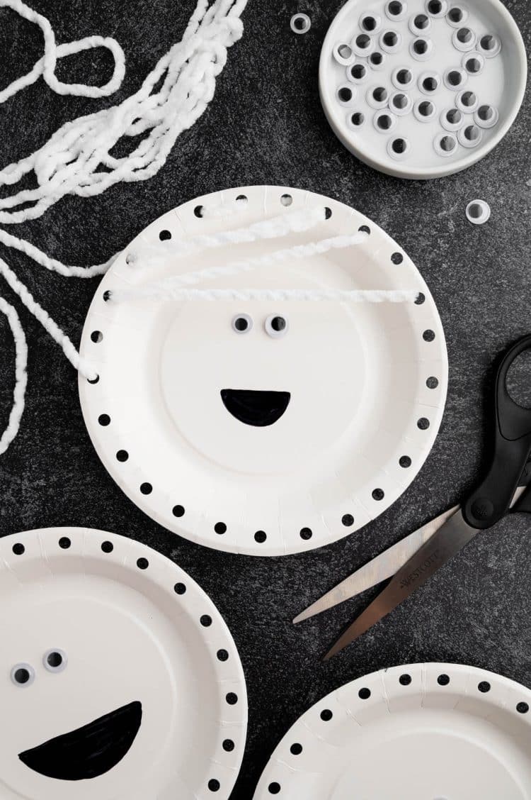 yarn strung through punched holes and across mummy paper plate