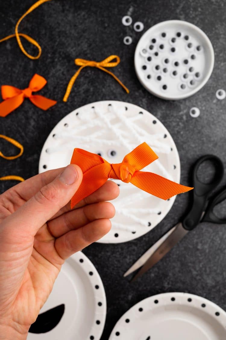 hand holding bow for mummy paper plate craft