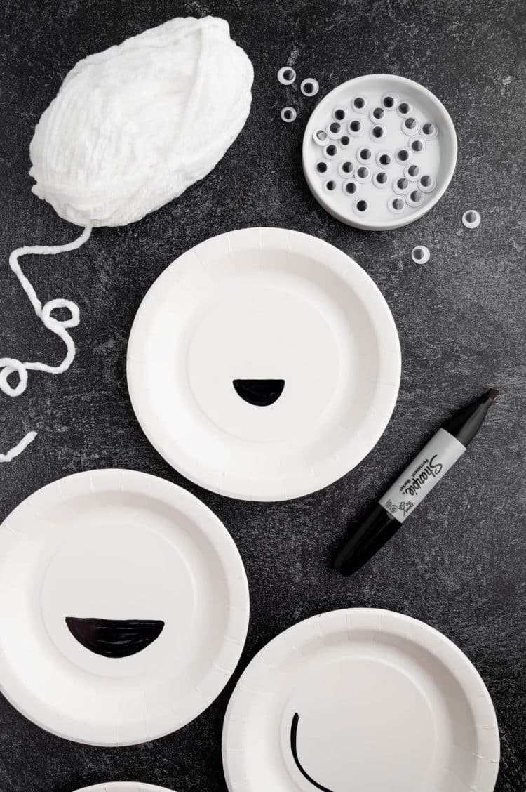 Paper plates with mouths cut out from them with other supplies