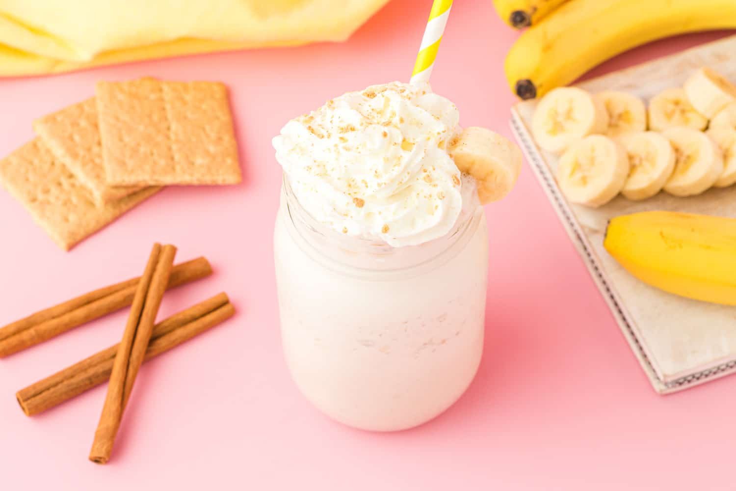 drink with whipped cream and bananas on a pink table