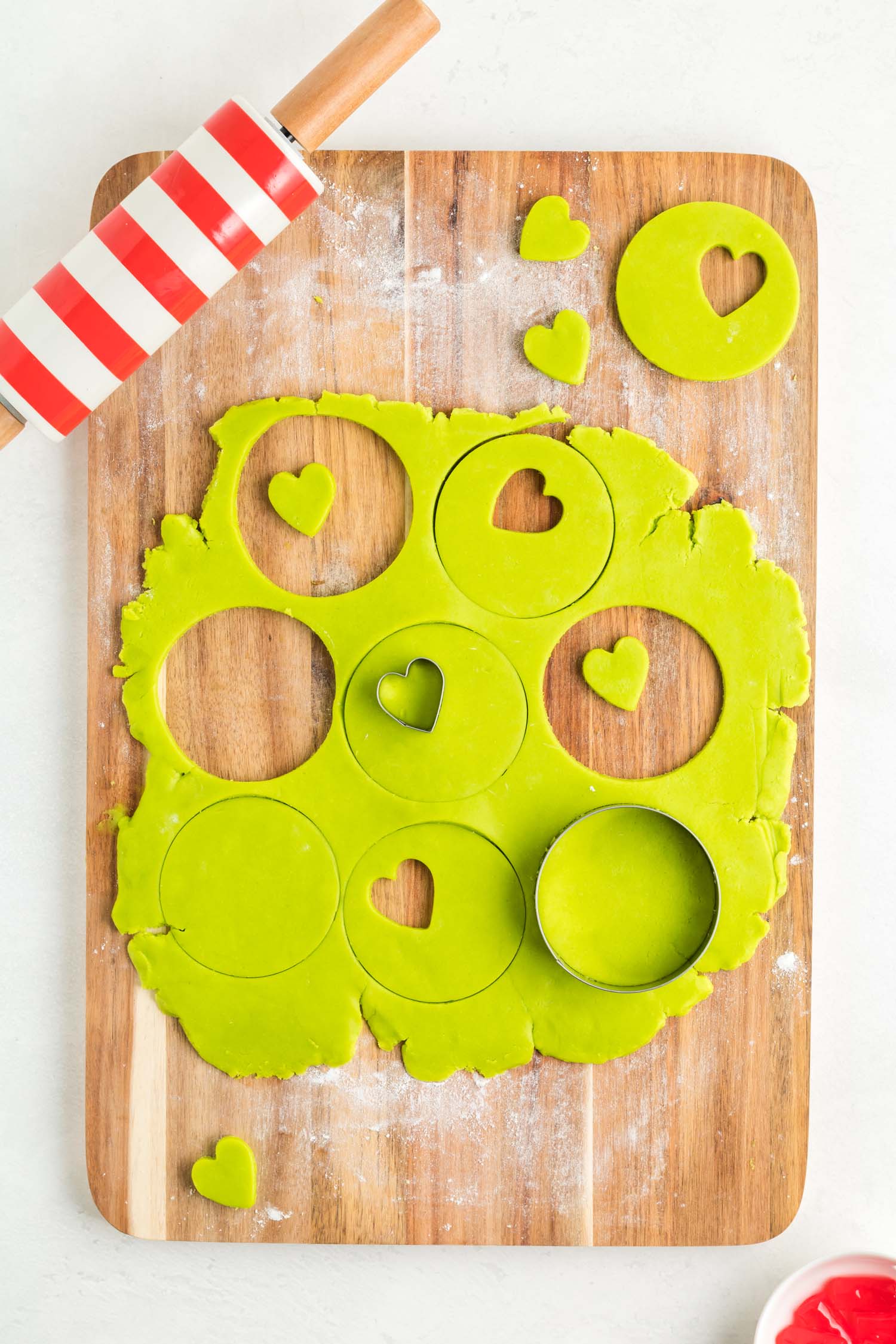 Cutting Cookie Heart Shapes out of Green Dough on Cutting Board