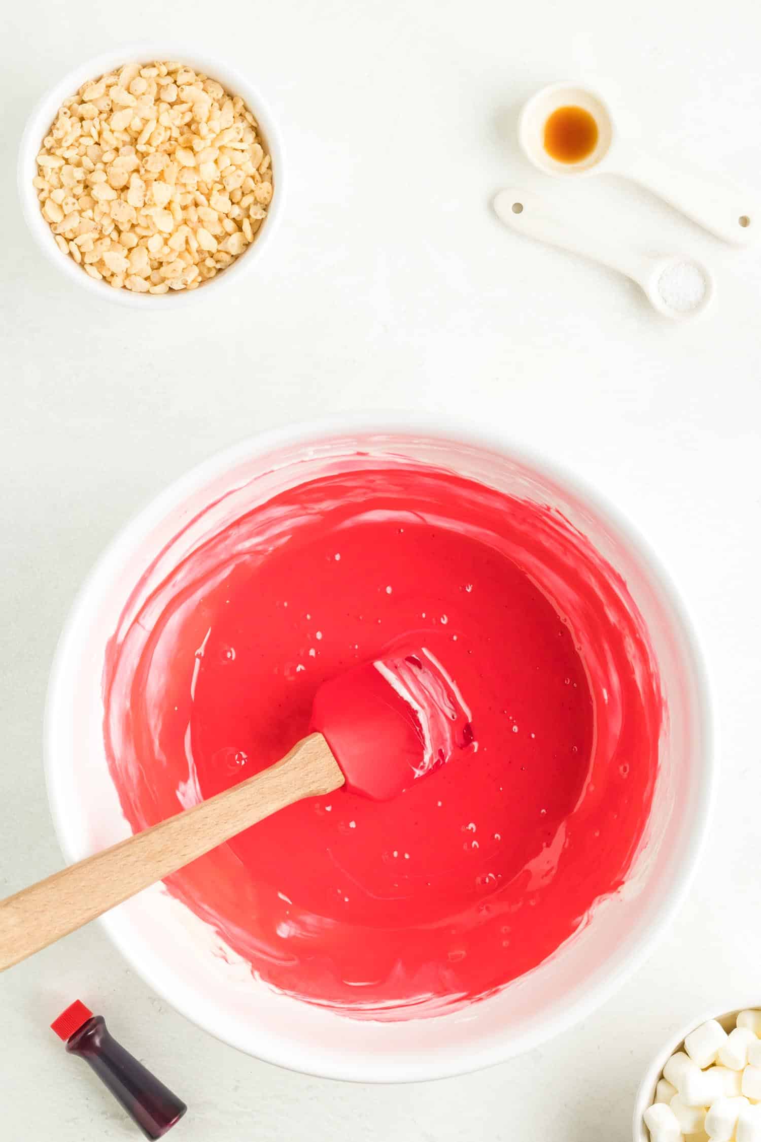 Overhead of red food coloring added into mixing bowl on white background