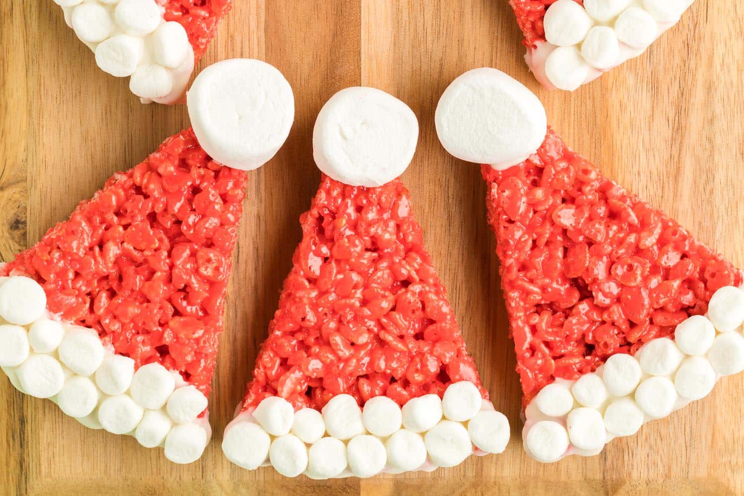 Several Rice Krispie hats displayed on wooden cutting board