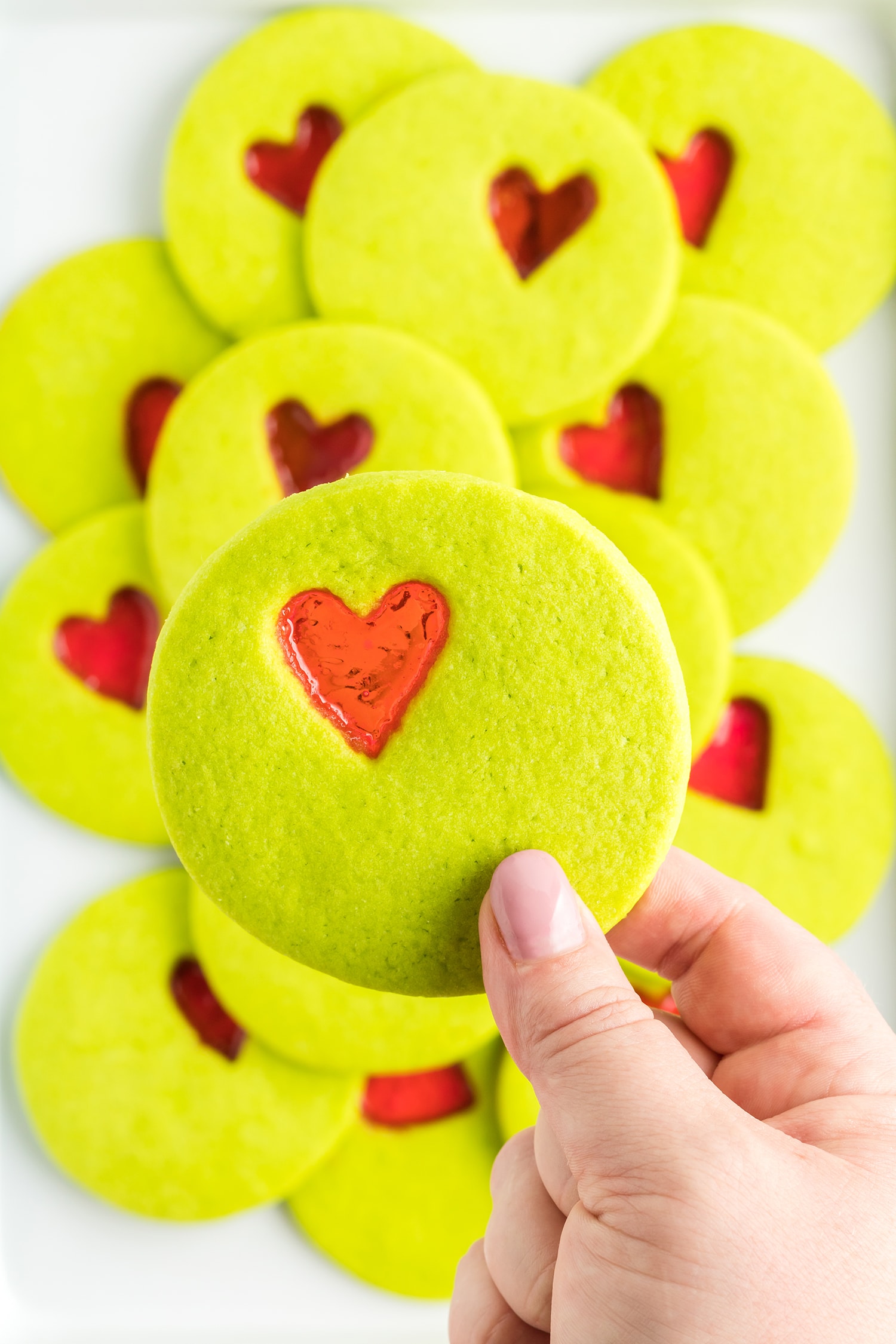 Hand holding stained glass Grinch cookies