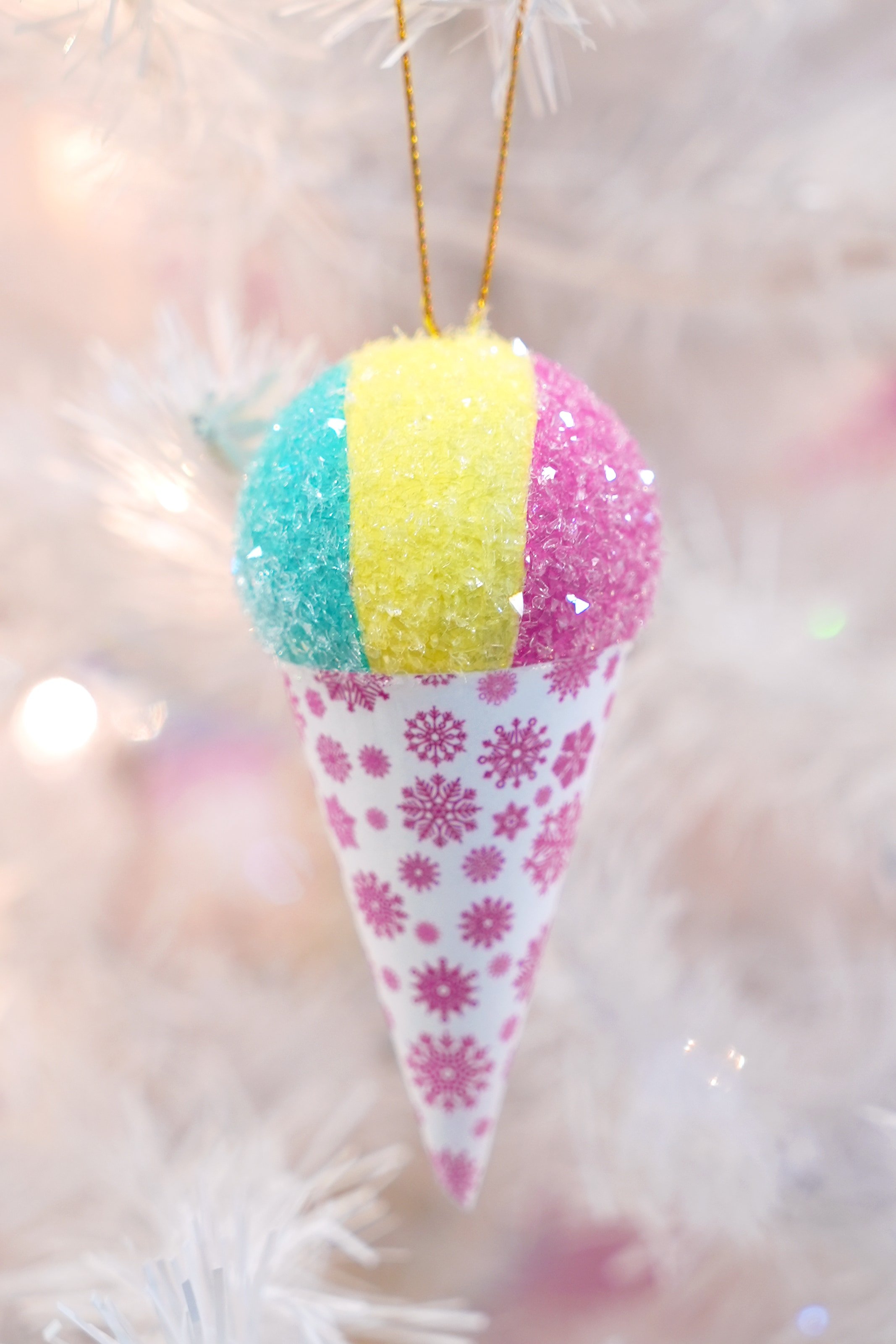 Close-up of glittered snow cone ornament on a white Christmas tree