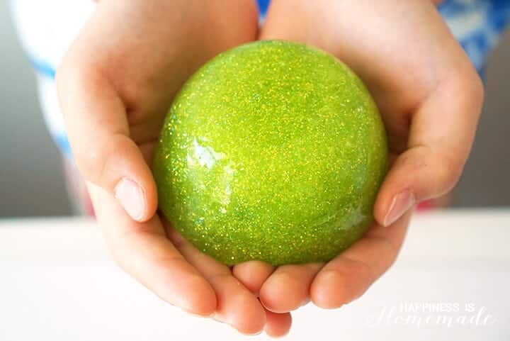 kids hands holding diy green slime