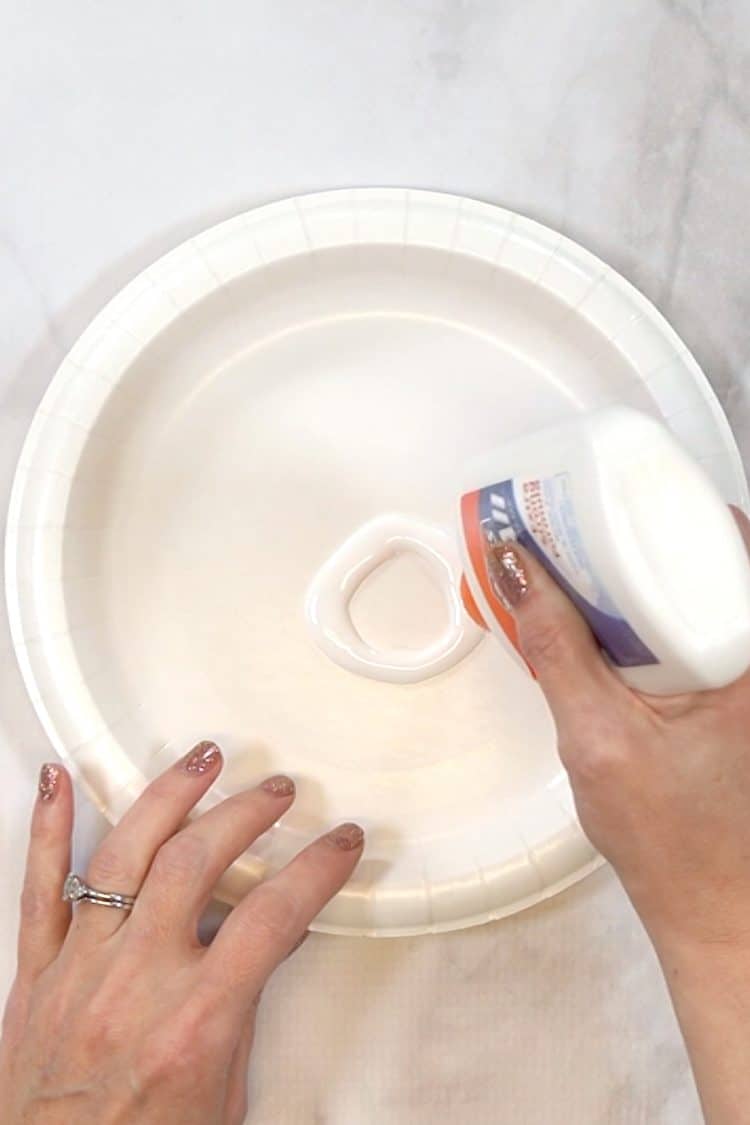 Hands adding a ring of glue to a paper plate