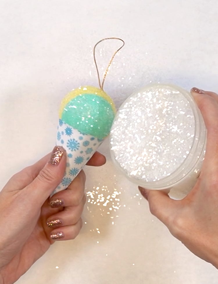 Close-up of hands pouring clear glitter on to a snow cone ornament