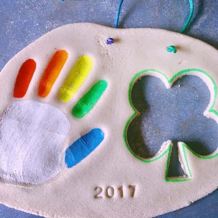 hand print pressed into salt dough with a shamrock shape cutout labeled with the year