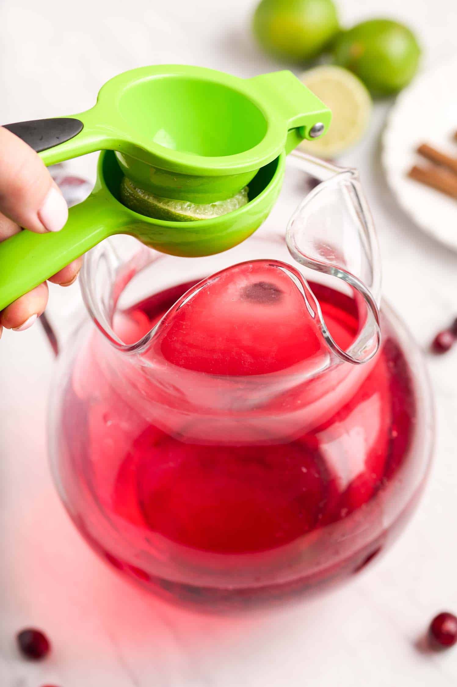 Squeezing limes into a pitcher of cranberry wine