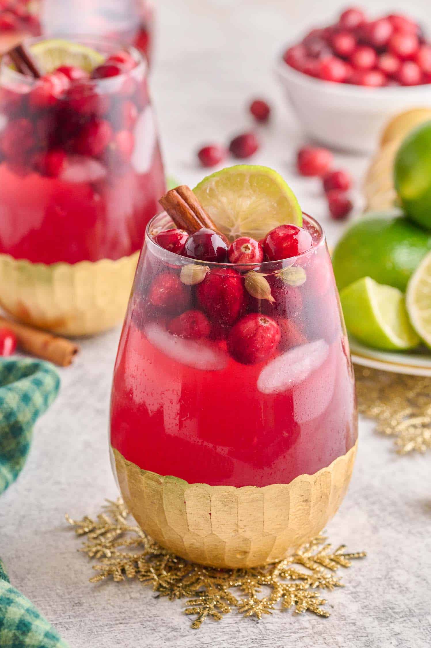 Spiced Cranberry Wine Spritzer in a wine glass with gold leafing on the bottom on a table