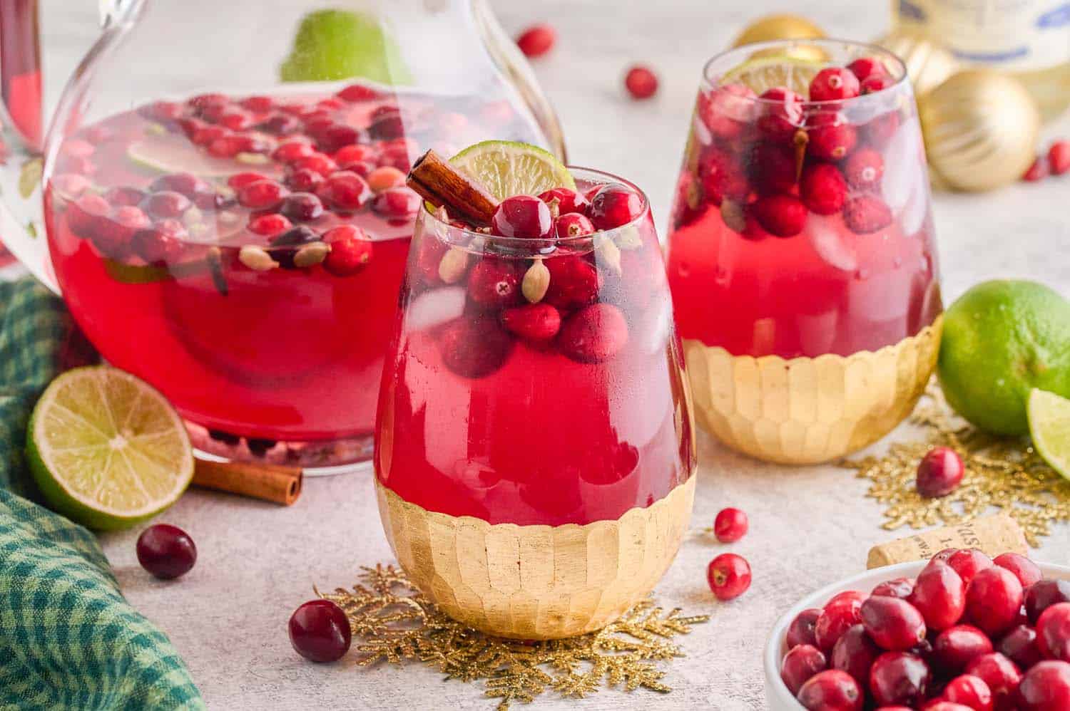 Two glasses and a pitcher of Spiced Cranberry Wine Spritzer on a table