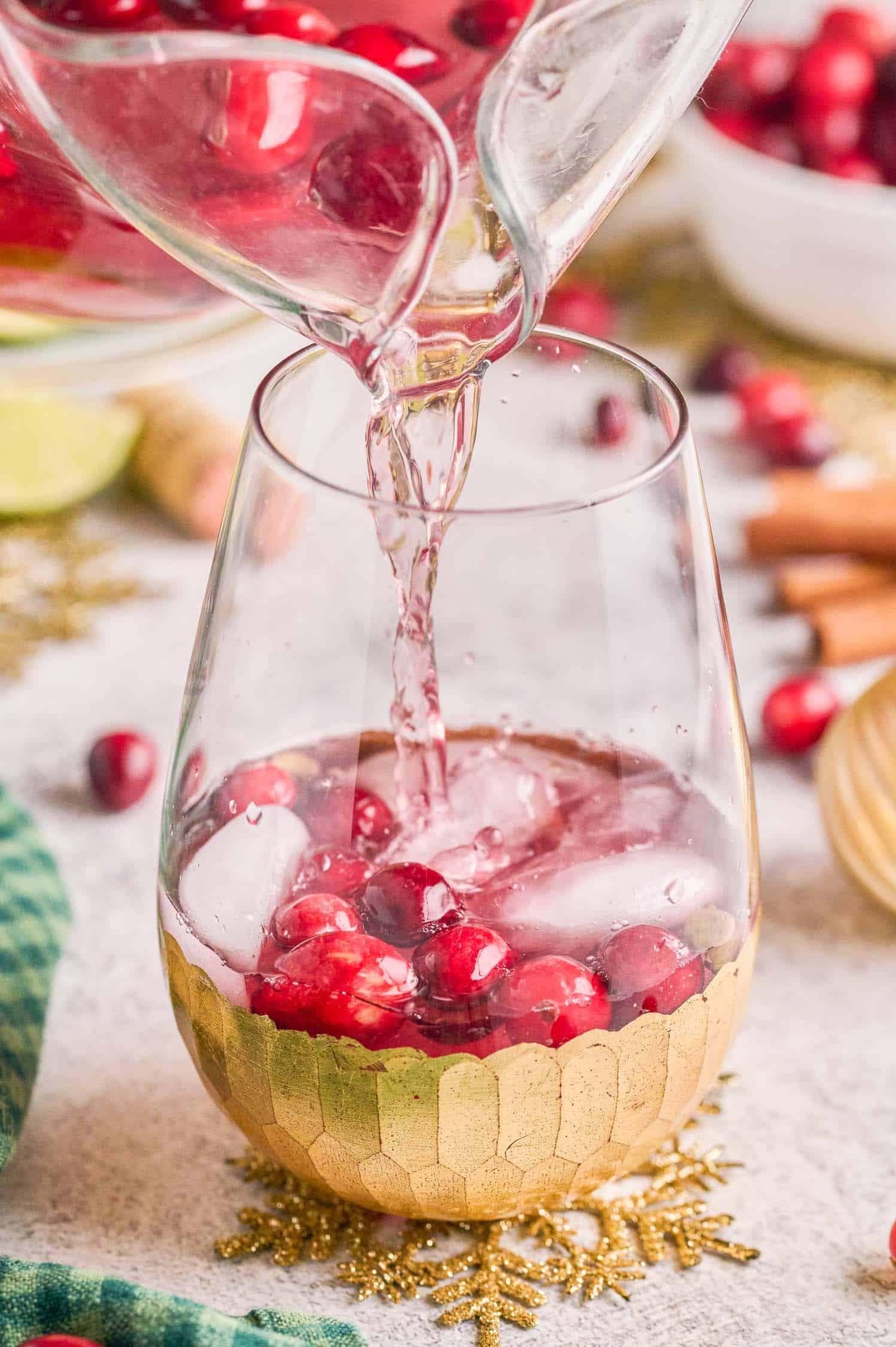 Pouring Spiced Cranberry Wine Spritzer from a glass pitcher into a wine glass