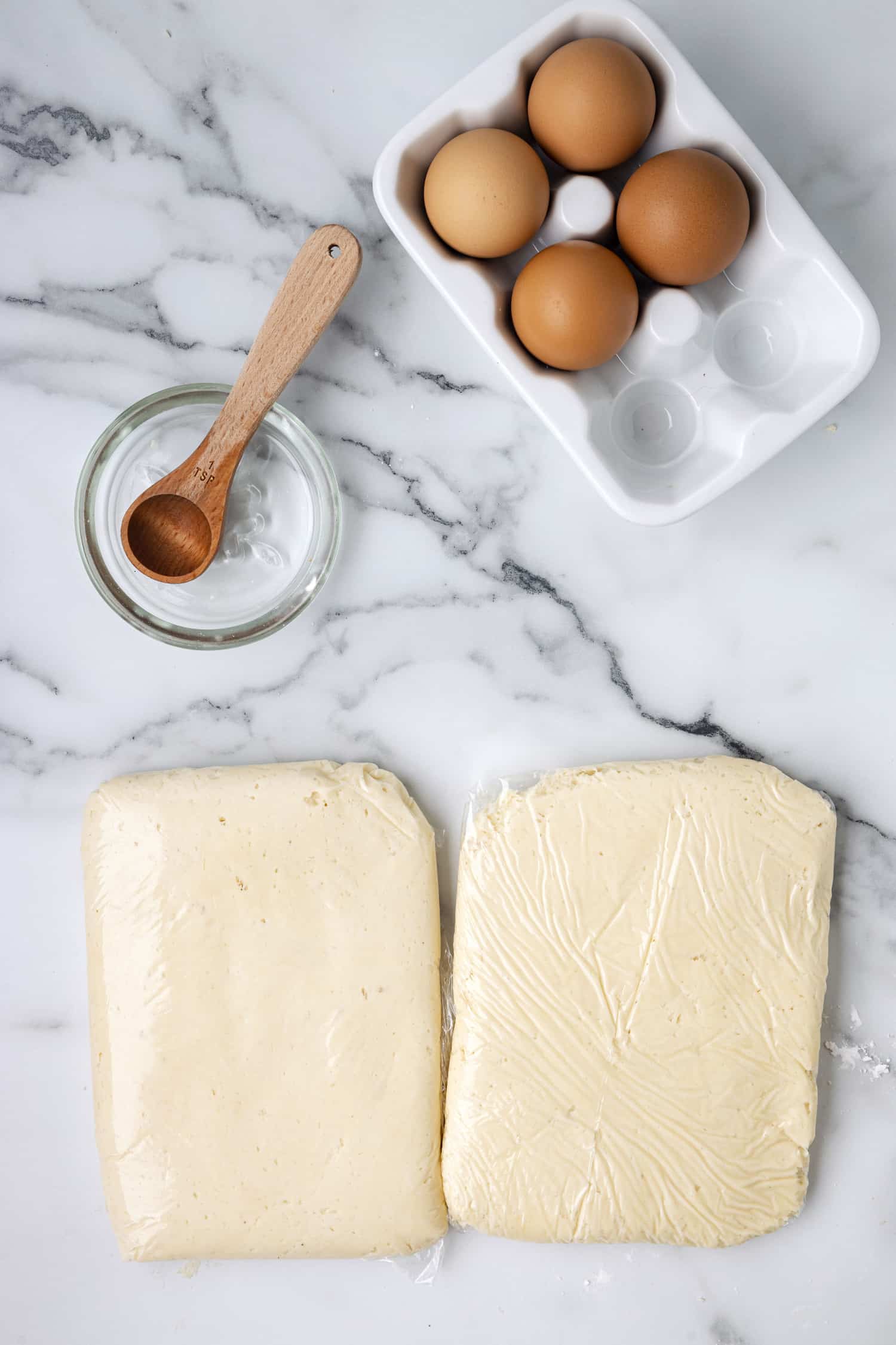 sugar cookie dough rolled out flat inside of plastic wrap