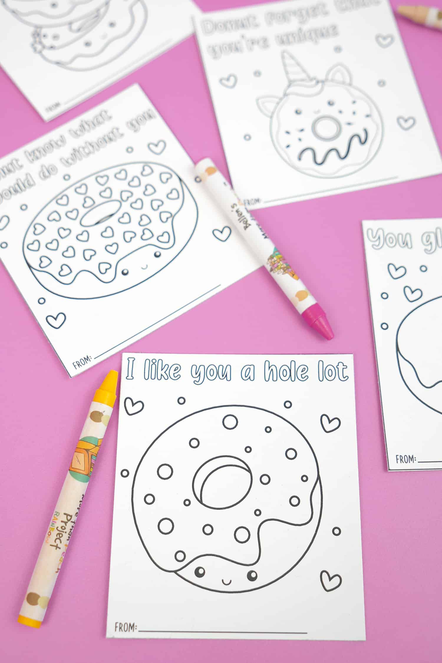 close up of valentine coloring cards on purple background with crayons
