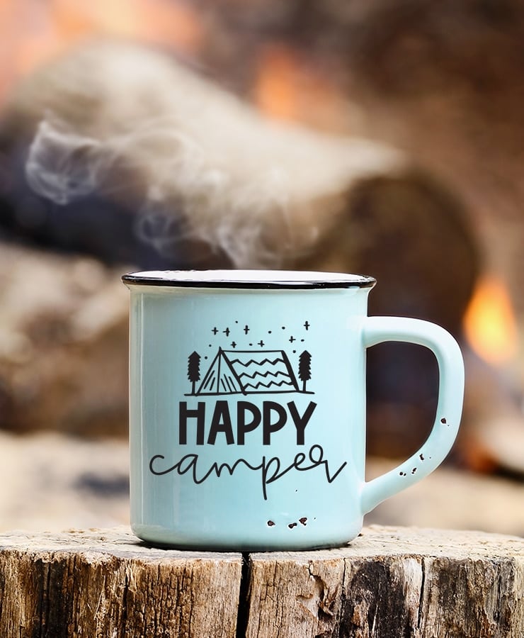camping mug with "happy camper" design in front of campfire