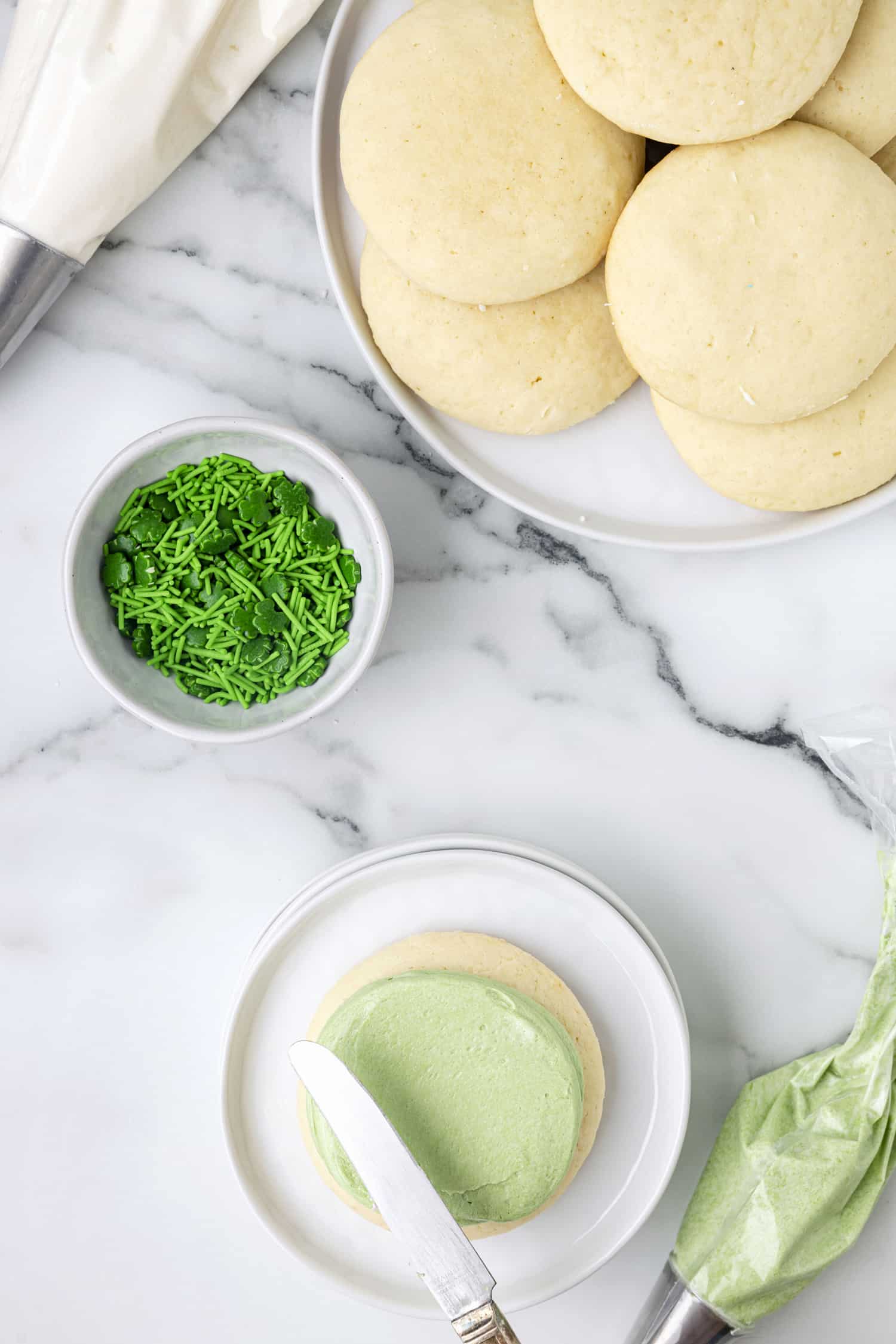 Green icing being spread on Lofthouse sugar cookie