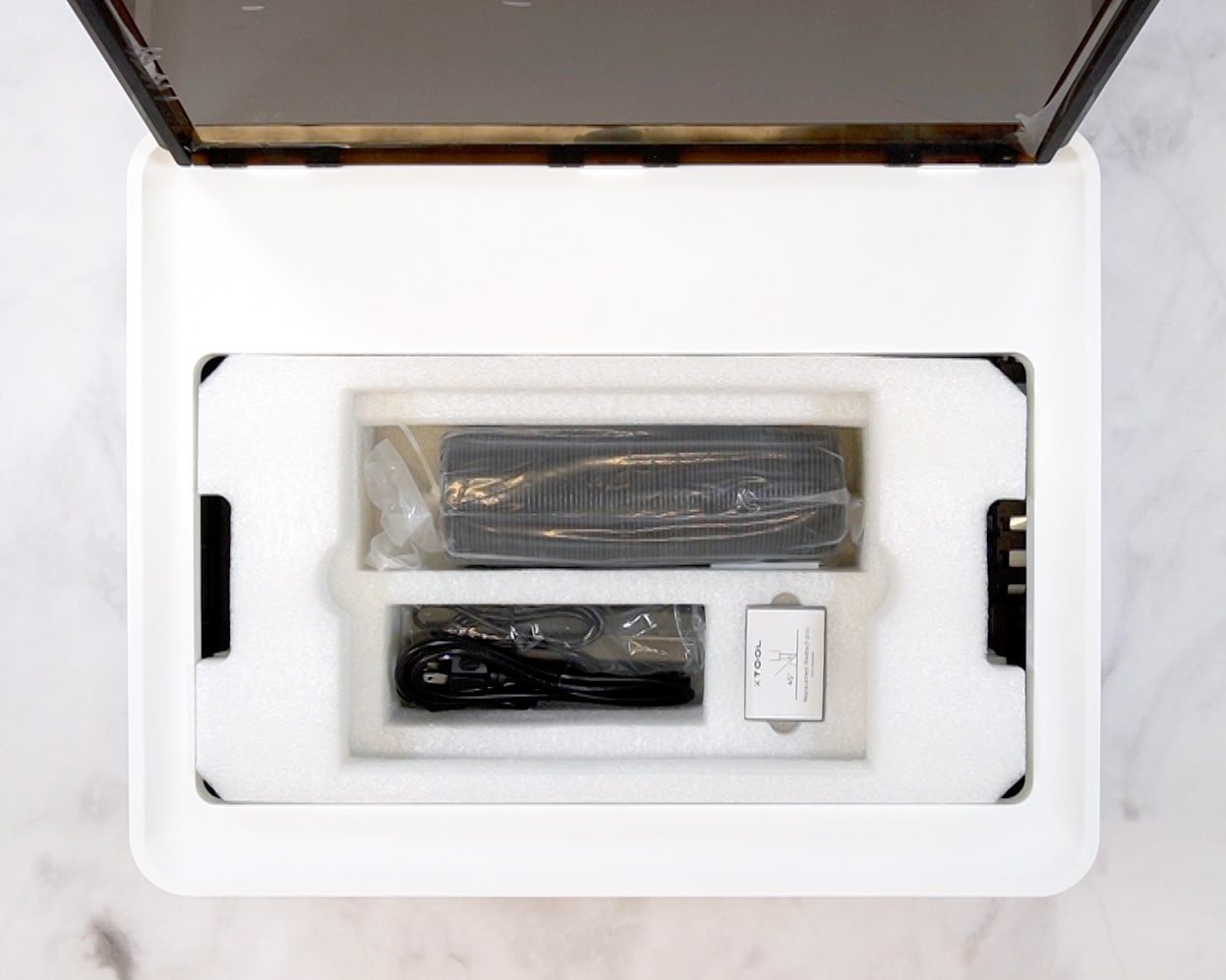 Overhead view of power cords and packaging materials inside the xTool M1 laser cutter