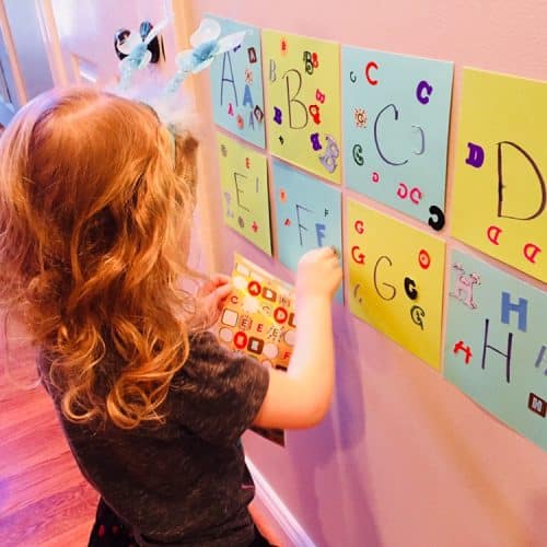 Child matching stickers to alphabet letters on the wall