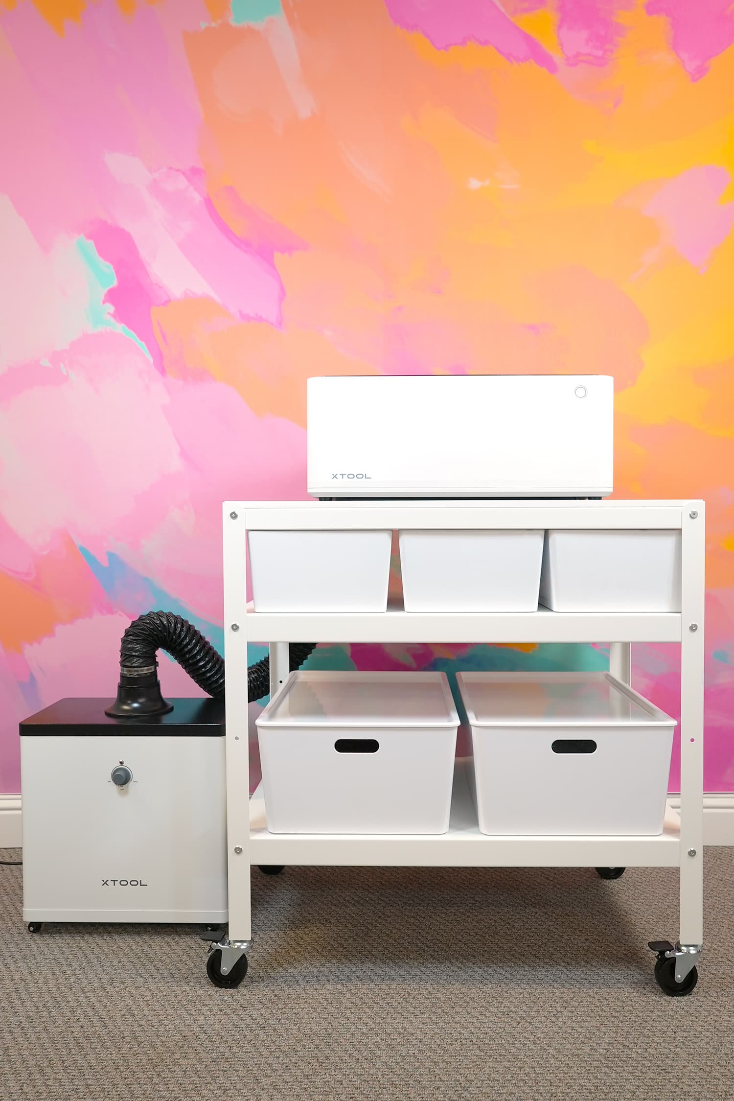 xTool M1 10w laser and smoke purifier in front of a colorful pink, orange, and yellow wall