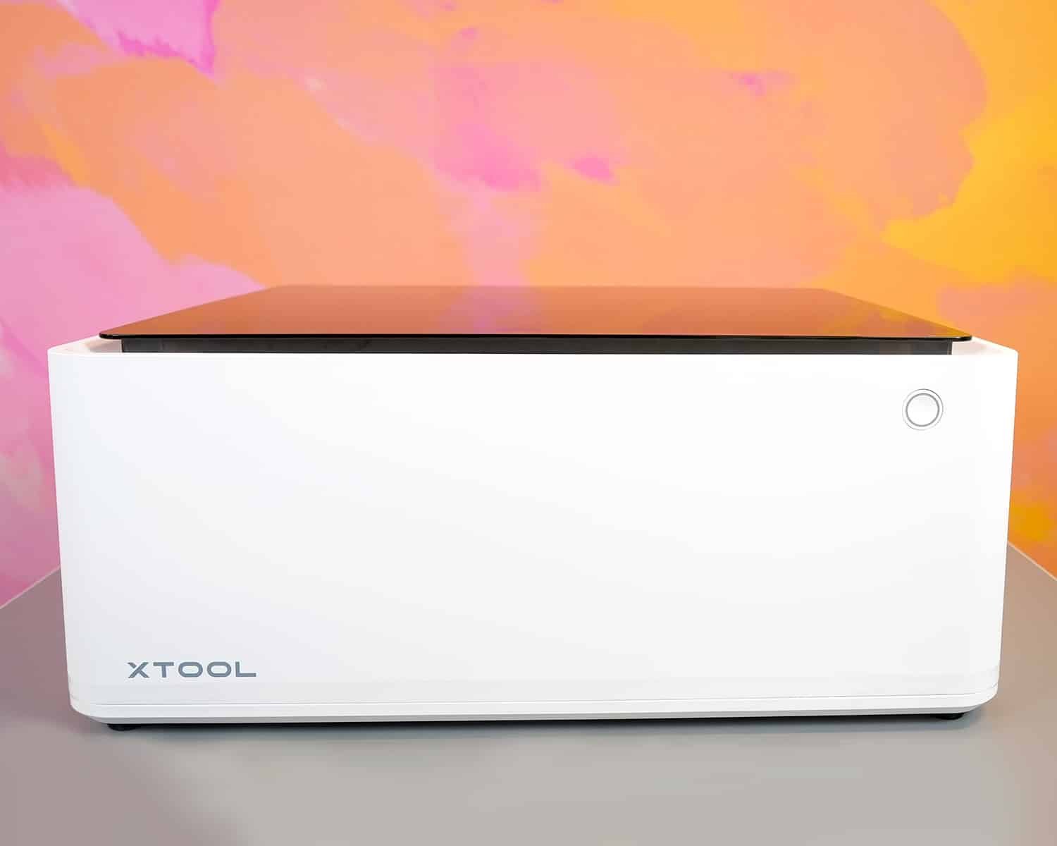 xTool M1 10w laser in front of a colorful pink, orange, and yellow wall