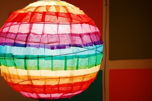 Spherical rainbow paper lantern lit up in a dark room