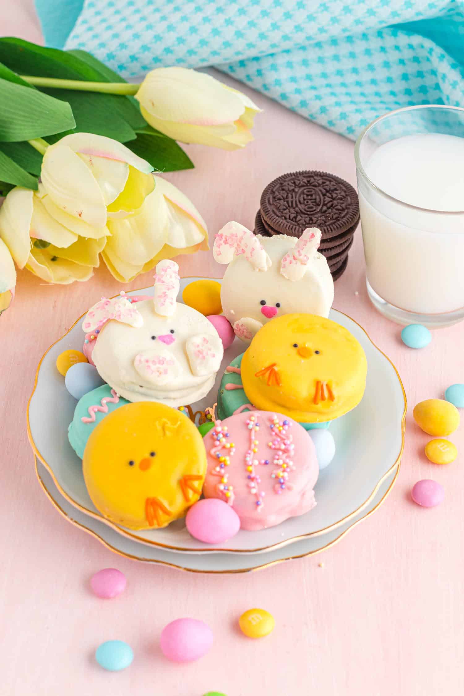 Easter Themed Chocolate Covered Oreos on a platter on a candy covered table with milk in background