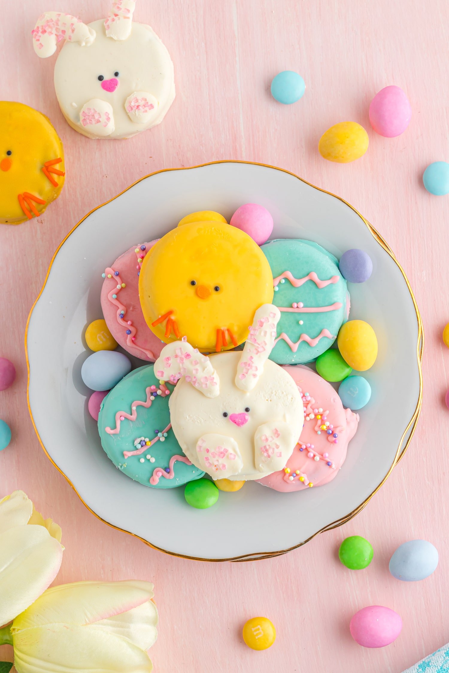 Plate of cute Easter Oreo cookies decorated to look like bunnies and chicks on a pink background