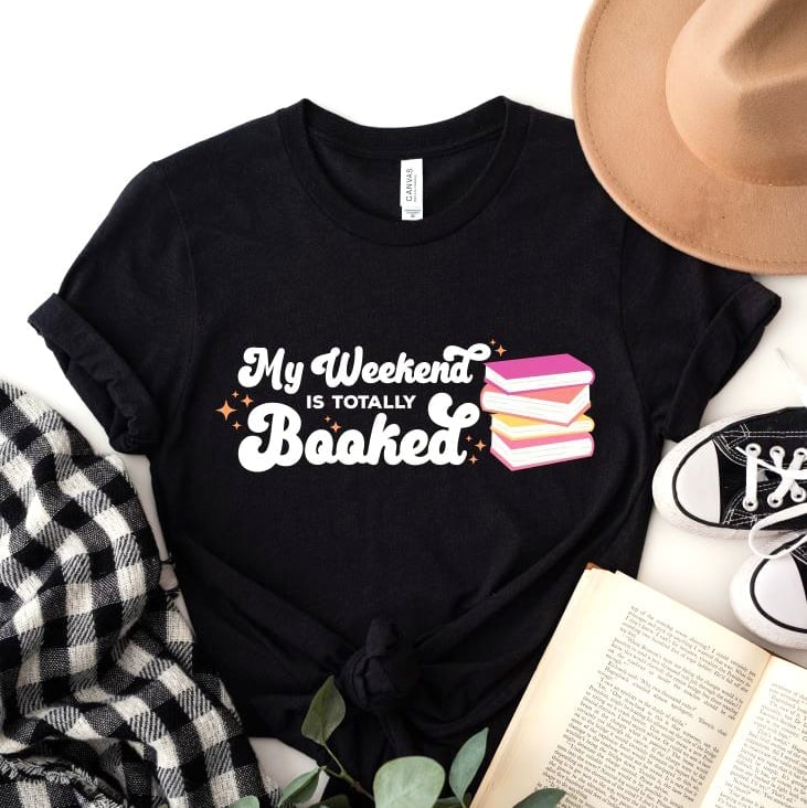 \"My Weekend Is Totally Booked\" SVG File printed on a black shirt and styled with hat, shoes, book, flower, and flannel