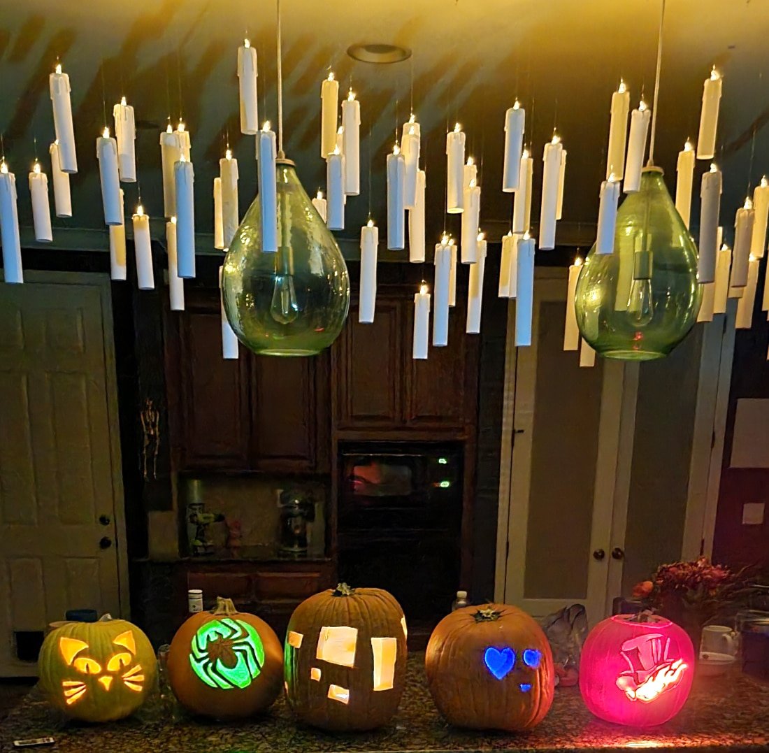 Harry Potter floating candles hanging from the ceiling with carved Halloween pumpkins on the counter below