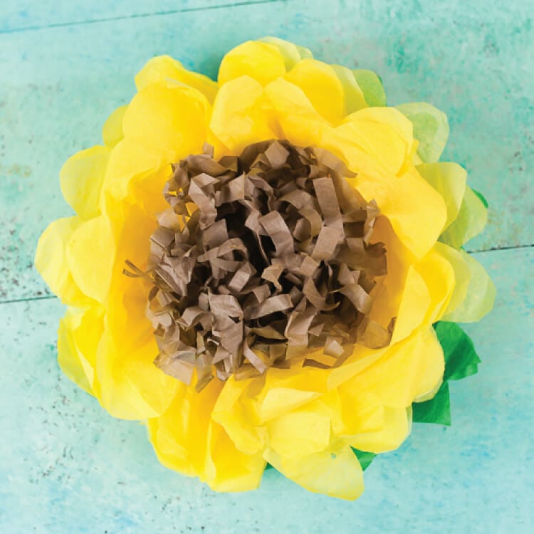 Yellow tissue paper sunflower on aqua background